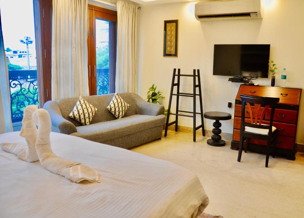 新德里Aashianaa Gracious Living的一间卧室配有一张床、一张沙发和一台电视