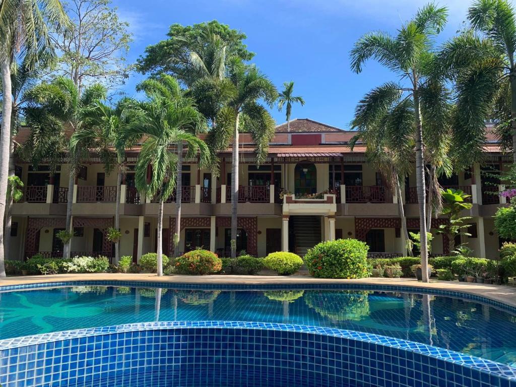 查汶拉达那简易别墅旅馆的棕榈树建筑前的游泳池