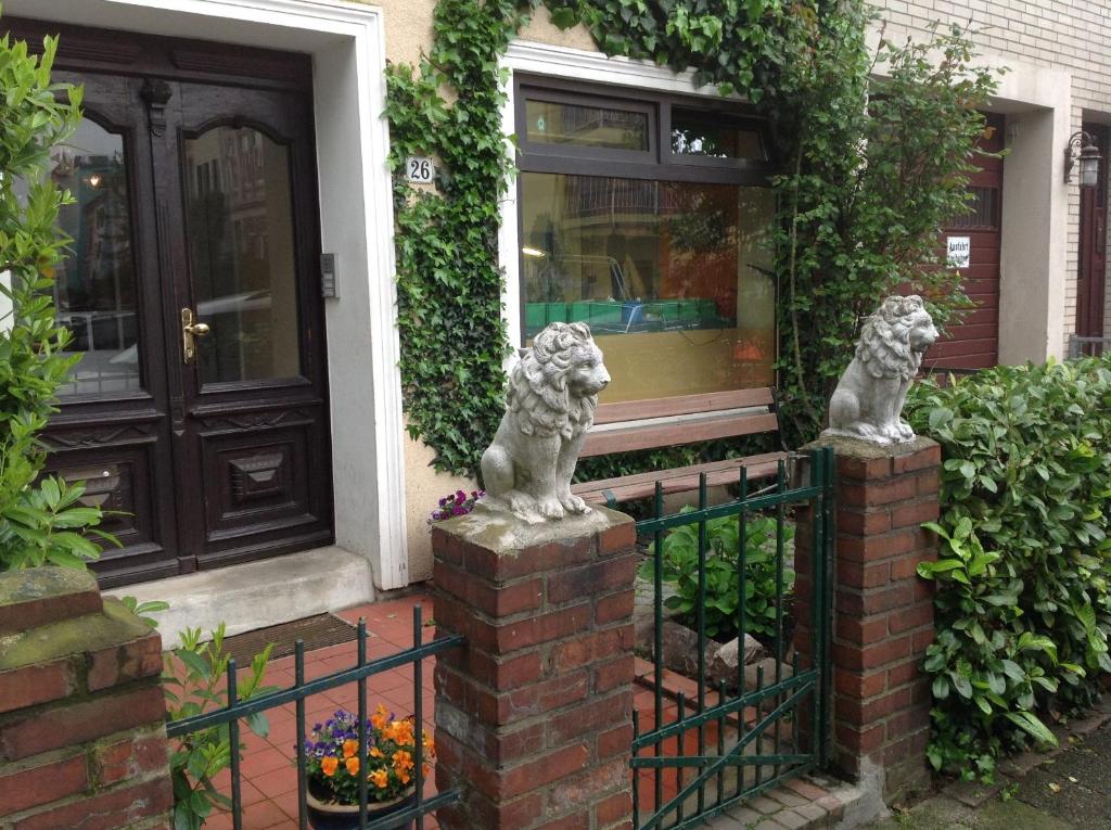 不莱梅Gästehaus La Dolce Vita的两座狮子雕像,在房子前面的栅栏上