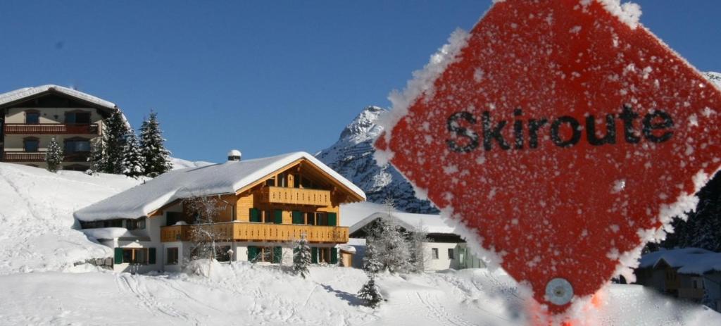 楚格Landhaus Alpenland的雪中的房子,前面有标志