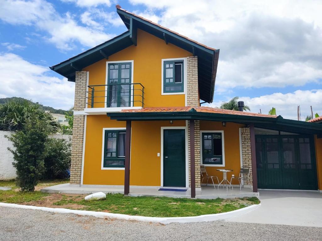 弗洛里亚诺波利斯Chalé em Condomínio com piscina - Ponta das Canas的街道上带阳台的黄色房屋