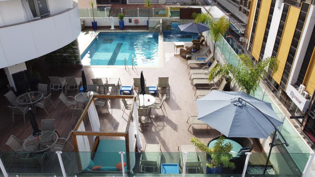 巴拉奈里奥-坎布里乌Hotel Sibara SPA & Convenções的享有带椅子和遮阳伞的游泳池的上方景致