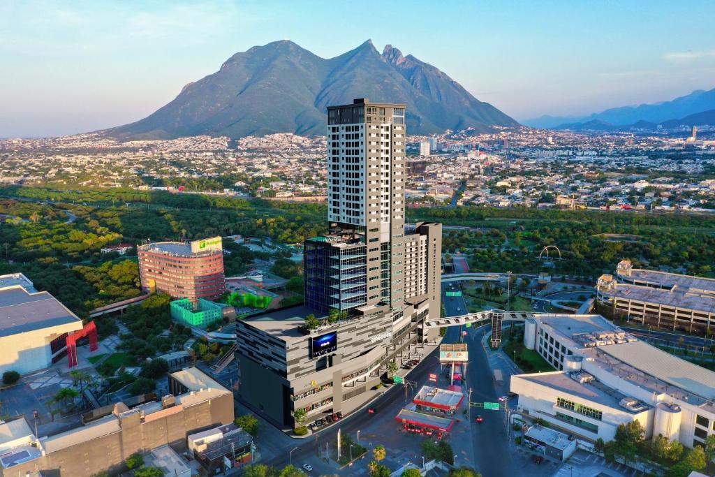 蒙特雷Holiday Inn Express - Monterrey - Fundidora, an IHG Hotel的城市的空中景观,背景是群山