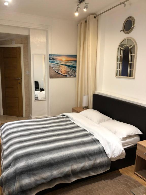 特威克纳姆Modern Apartment in Twickenham Highstreet的一间卧室配有一张带条纹毯子的大床
