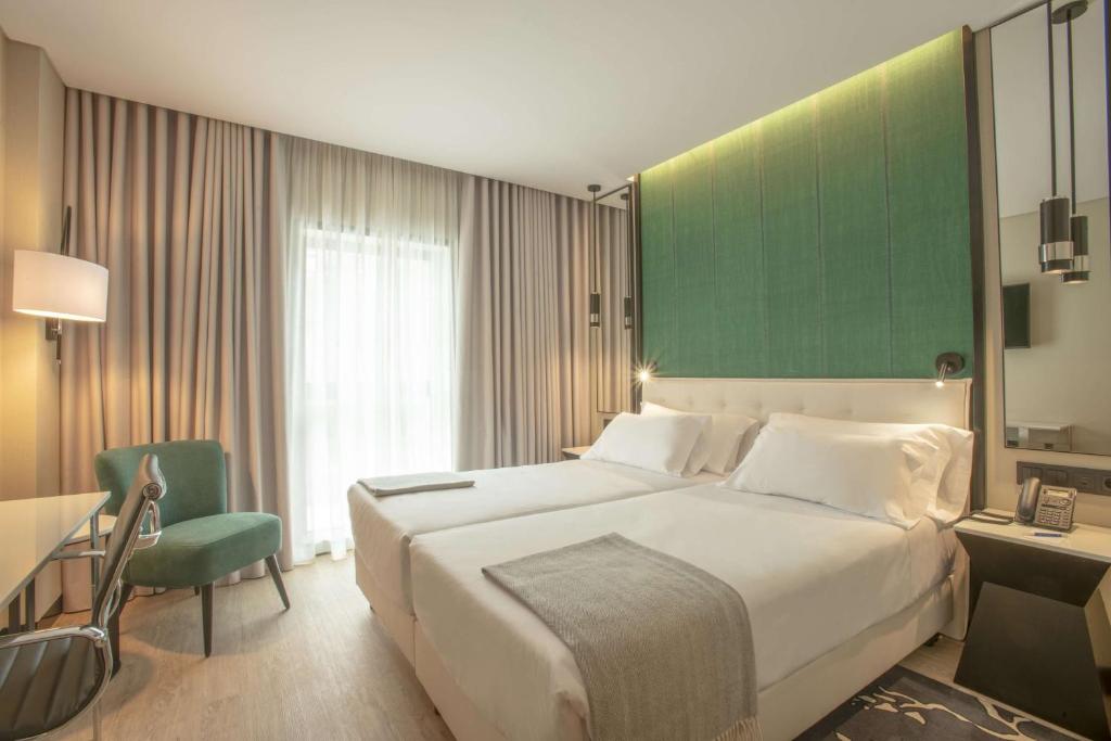 波尔图NH Porto Jardim的一间卧室设有一张大床和绿色的墙壁