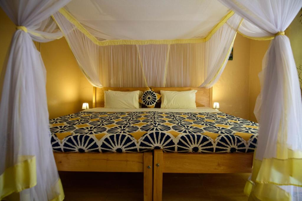 恩德培Cycad Entebbe Guest House的一间卧室配有一张带天蓬的床