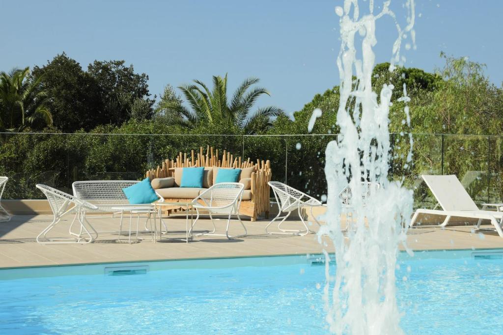 利勒鲁斯Résidence Storia d'Estate的游泳池旁的喷泉,配有椅子和沙发