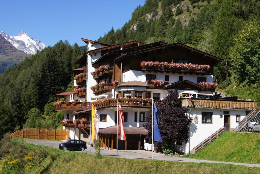 海利根布卢特Alpin Panoramahotel Lärchenhof的山丘上一座有旗帜的建筑
