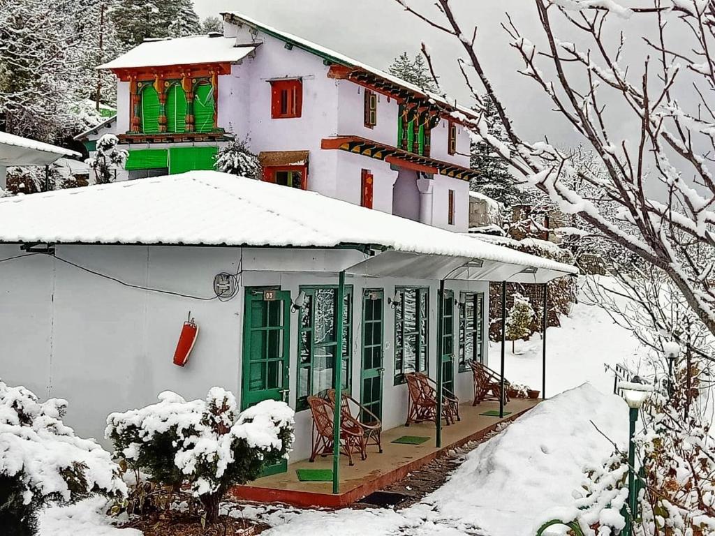 乔斯希马特Himalayan High, Auli, By Himalayan Eco Lodges的一座房子,有绿色的窗户,下雪