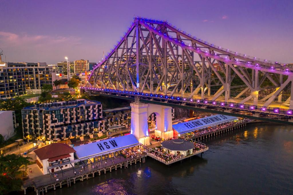 布里斯班Hotel X Brisbane Fortitude Vly, Vignette Collection - an IHG Hotel的一座夜间与城市在水面上的桥梁