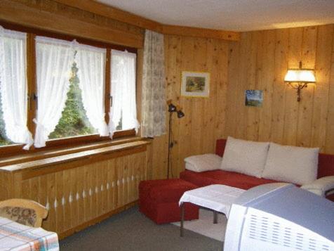 因斯布鲁克布里吉塔乡村别墅酒店的客厅设有红色的沙发和窗户。