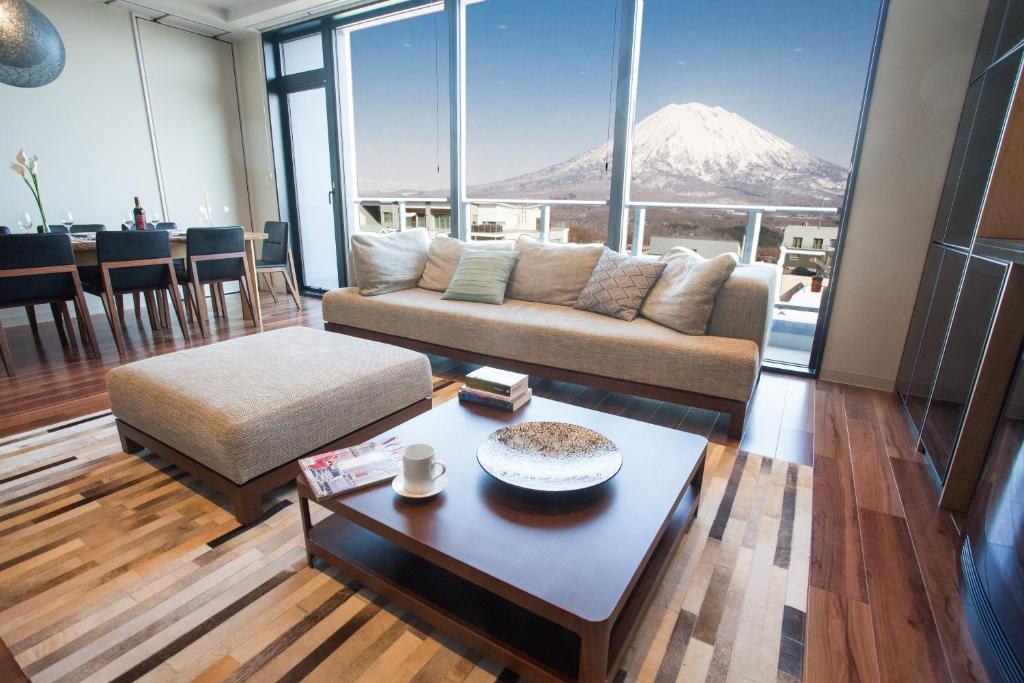 二世古hirafu188的客厅配有沙发和桌子,享有山景。