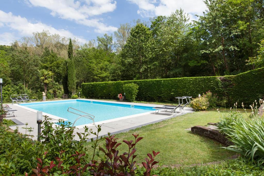 塔皮安诺Art Hotel Pandos的灌木花园中的游泳池