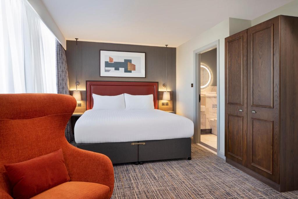 伯明翰Leonardo Royal Hotel Birmingham的一间卧室配有一张床和一把椅子