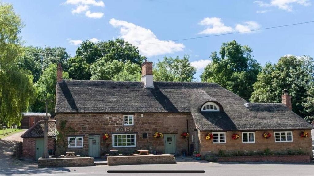 达文特里The Plough Inn Boddington的一座带屋顶的旧砖砌建筑