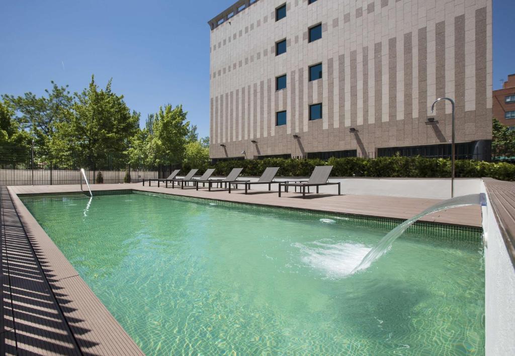 马德里巴拉哈斯机场NH酒店 的一座大楼前的游泳池,带喷泉