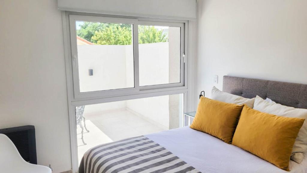 圣罗莎Poas - Alquiler temporario的一间卧室设有窗户和一张带黄色枕头的床