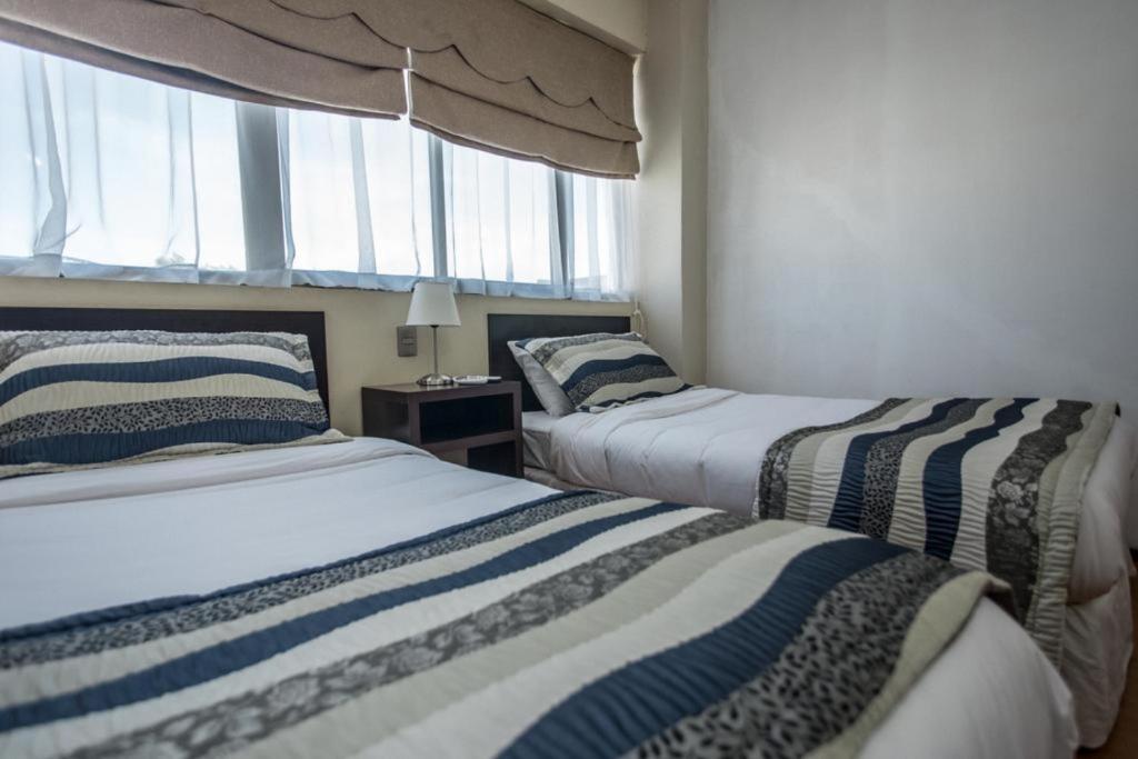 塔尔卡Hotel Capelli Express的带窗户的客房内的两张床