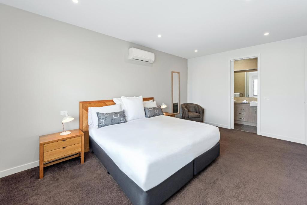 墨尔本Fawkner Executive Suites & Serviced Apartments的卧室配有一张白色的大床和床头柜。