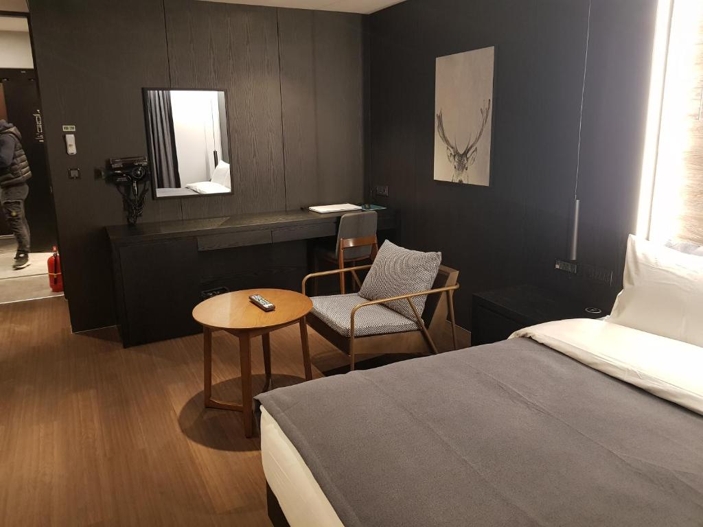 安城市Anseong City Hotel的卧室配有1张床、1张桌子和1把椅子