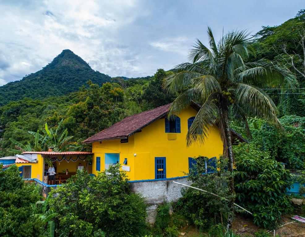阿布拉奥Casa dos Franceses Ilha Grande的山前有棕榈树的黄色房子