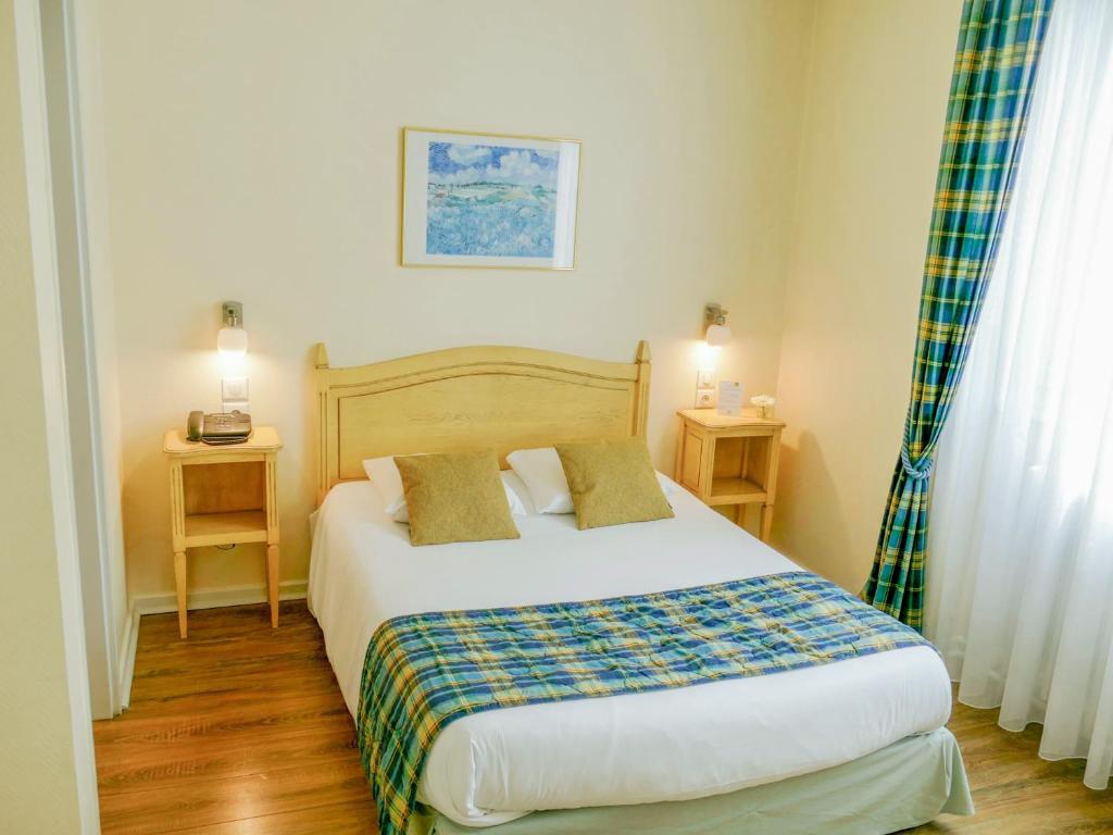 圣路易柏辽兹巴塞尔机场酒店的一间卧室配有一张带2个床头柜和2张桌子的床