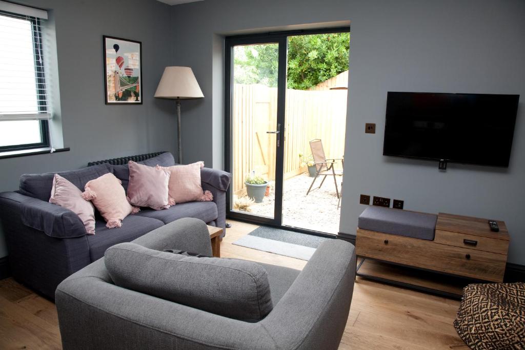 巴斯Little Elm - luxury home from home, free parking, 30-40 mins walk from Bath city centre的客厅配有2张沙发和1台平面电视