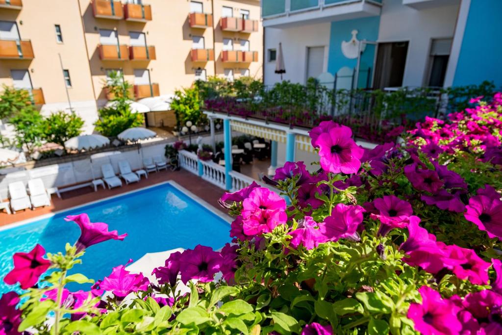 里米尼Hotel Villa dei Fiori - sul mare con piscina的一个带游泳池和鲜花的阳台