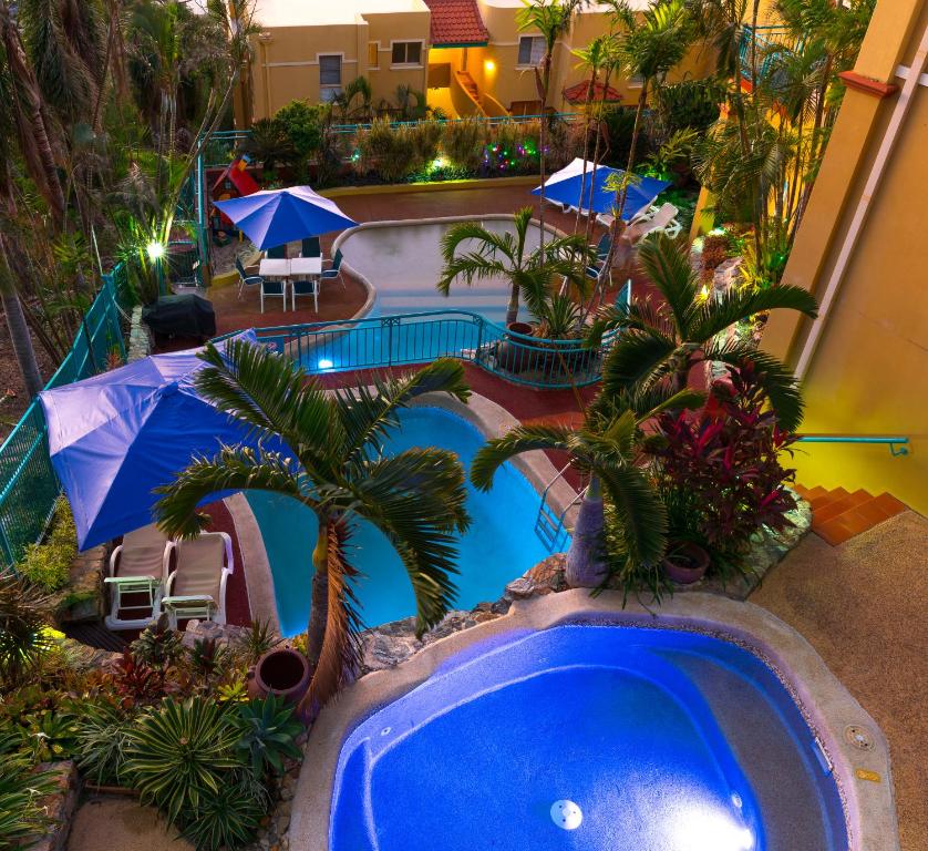 埃尔利海滩托斯卡纳乡村酒店的享有游泳池的顶部景色,游泳池拥有棕榈树和遮阳伞