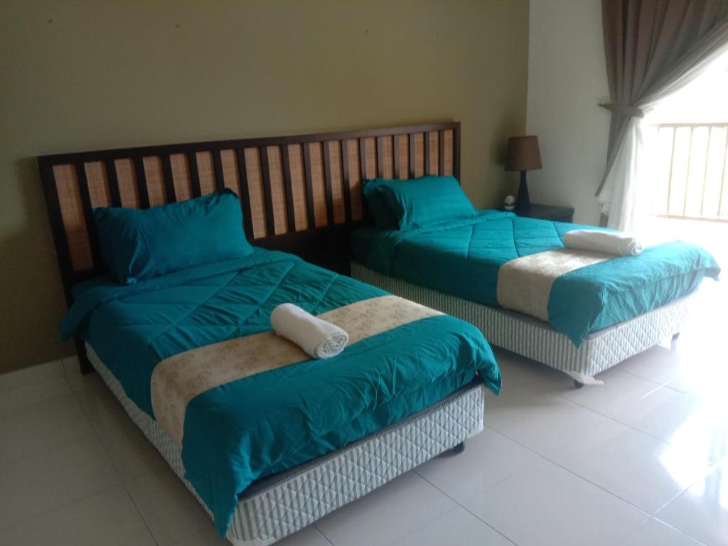 万津Izz room studio Gold Coast Morib Resort的配有蓝色枕头的客房内的两张床