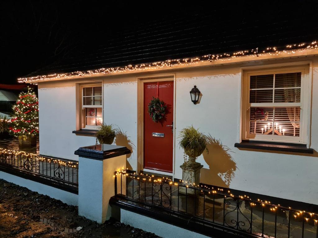 莱特肯尼Kiltoy Cottage, Cosy 2 bedroomed Gate Lodge Cottage的一座有圣诞树和红色门的房子