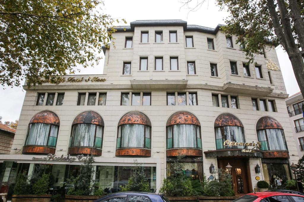 伊斯坦布尔Ottoman's Life Hotel S Class的一座白色的建筑,设有窗户,门前有汽车停放