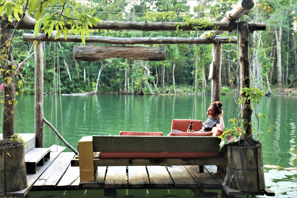 里约杜尔塞El Hotelito Perdido的坐在湖岸边的长凳上的女人
