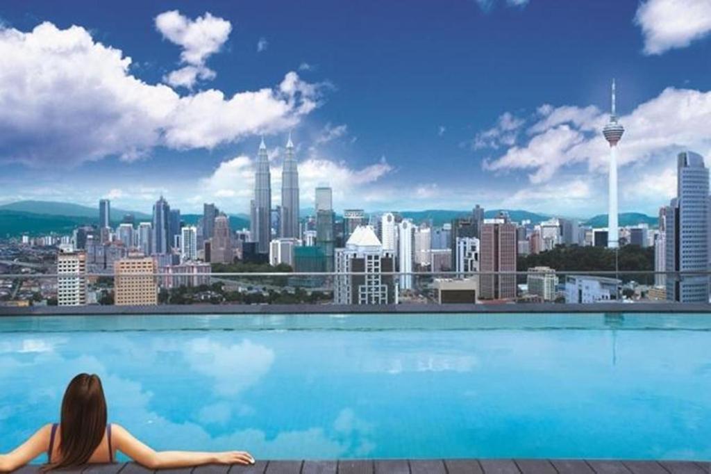吉隆坡Regalia Upper View Hotel的坐在游泳池里俯瞰城市的女人