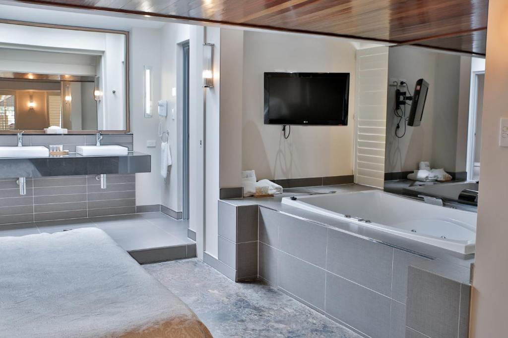洛坎普顿中央公园汽车旅馆 的一间带浴缸和两个盥洗盆的浴室以及一台电视。