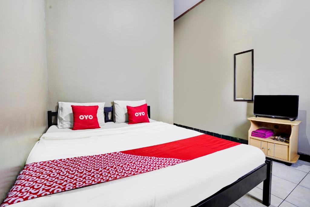 ManiskalerSuper OYO 1I3676 Wisma Al-fahmi Syariah的一间卧室配有一张带红色枕头的床和一台电视。