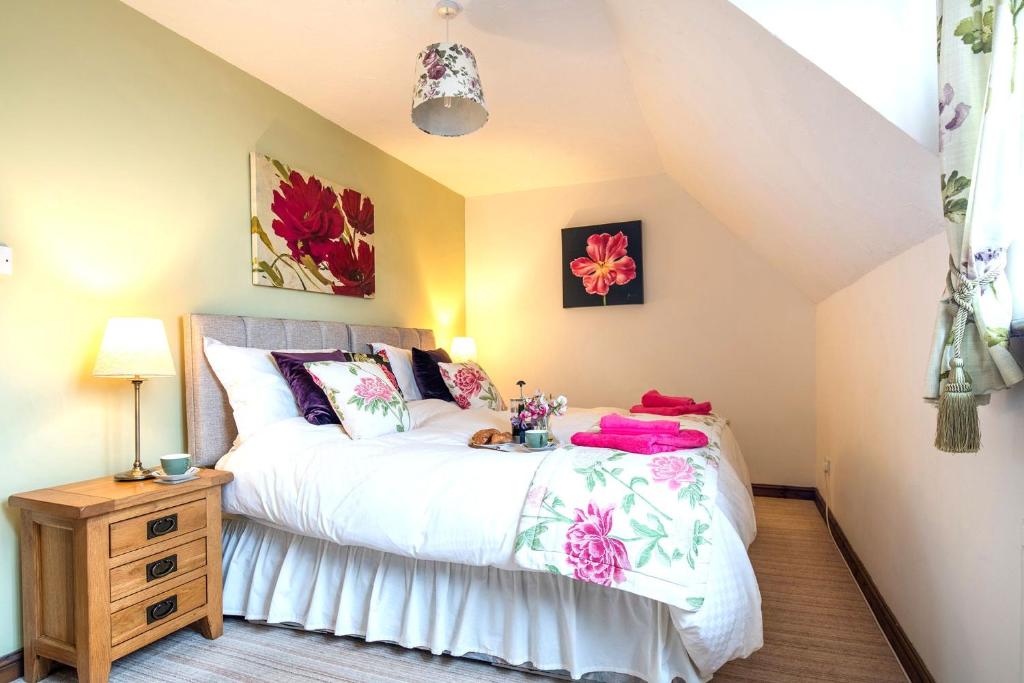 HolkerCharming Cottage near Cartmel with free Spa access的一间卧室配有白色床单和鲜花。