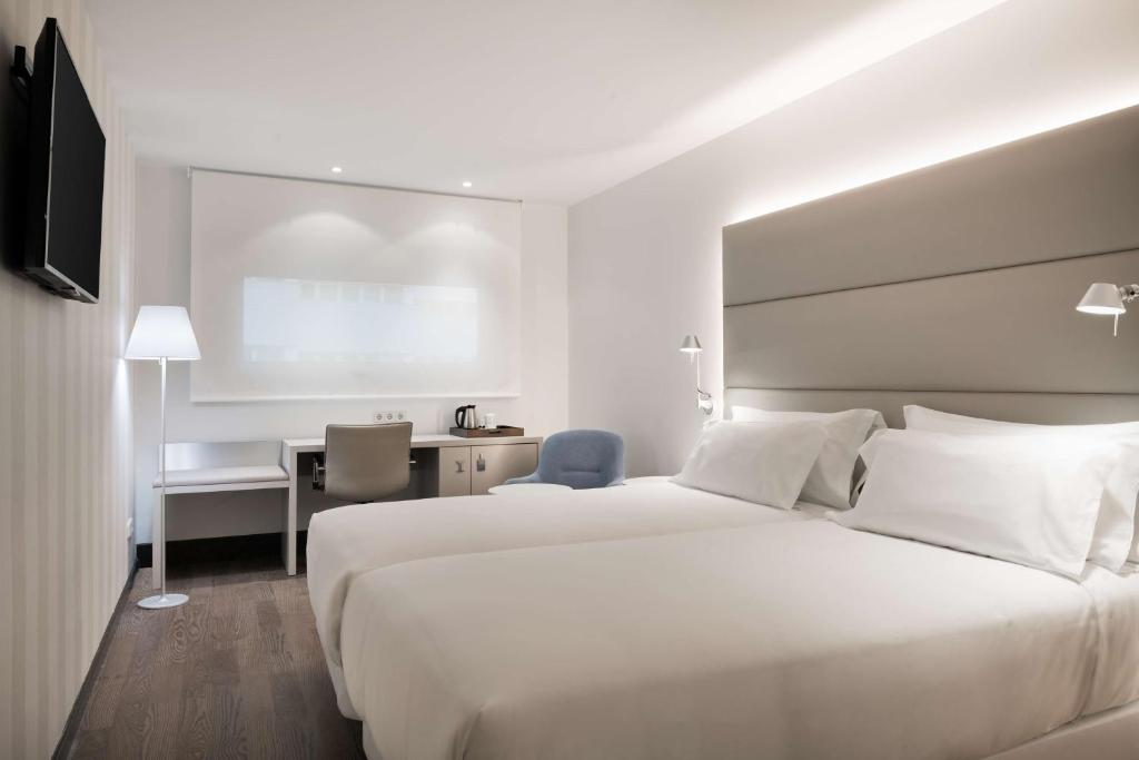 雷阿尔城NH皇城酒店的酒店客房设有一张白色大床和一张书桌