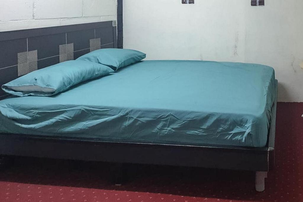 Sungai LutusRocky Guest House Syariah Mitra RedDoorz的一张带蓝色床单和枕头的床