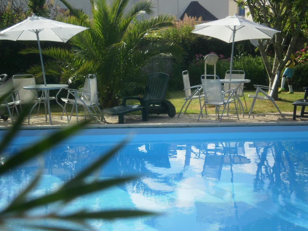 贝诺代Les Bains de Mer Riviera Bretonne的一个带桌椅和遮阳伞的游泳池