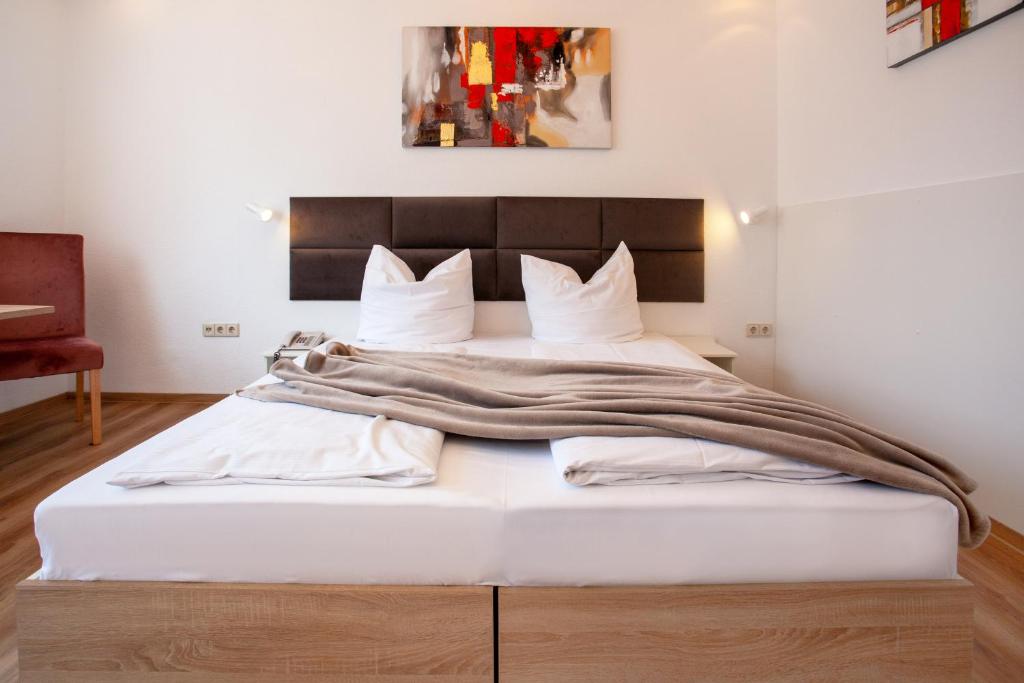 斯图加特Relax Hotel & SPA Stuttgart的卧室配有一张白色大床和木制床头板