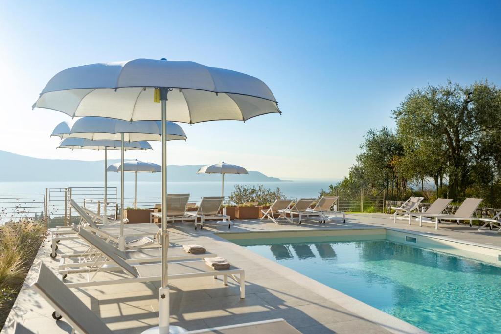 托斯科拉诺-马德尔诺Relais Zenner的游泳池旁的游泳池配有椅子和遮阳伞