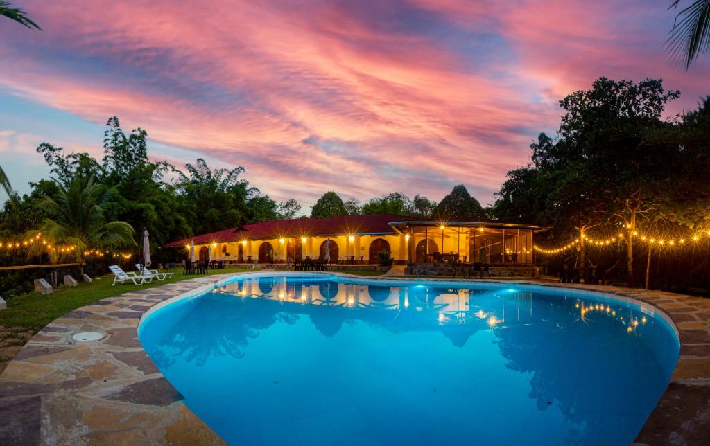 塔拉波托Lodge Casa de Campo "APU SAMAY"的一座享有日落美景的建筑前的游泳池