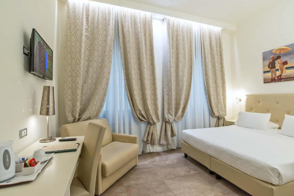 佛罗伦萨学院酒店的一间卧室配有一张床、一张桌子和一把椅子