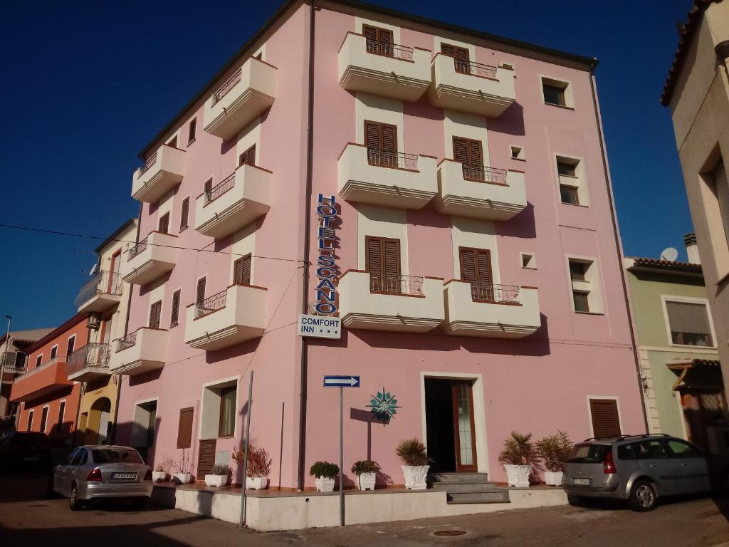 圣特雷莎加卢拉斯卡诺舒适酒店的一座粉红色的建筑,前面有汽车停放