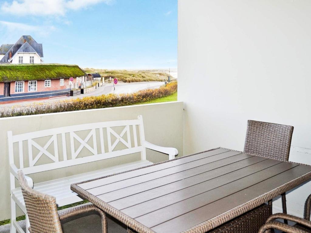 凡岛4 person holiday home in Fan的阳台上配有一张木桌和椅子,享有海景