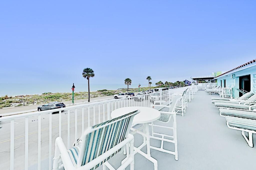 圣徒皮特海滩Pass-A-Grille Beach Retreat Unit 8的阳台上的一排白色的椅子和桌子