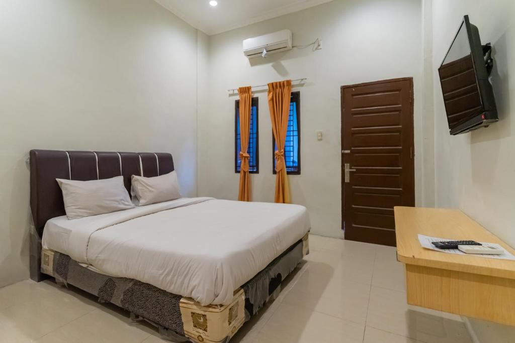 棉兰Vandolia Guest House Mitra RedDoorz的一间卧室配有一张床和一台电视