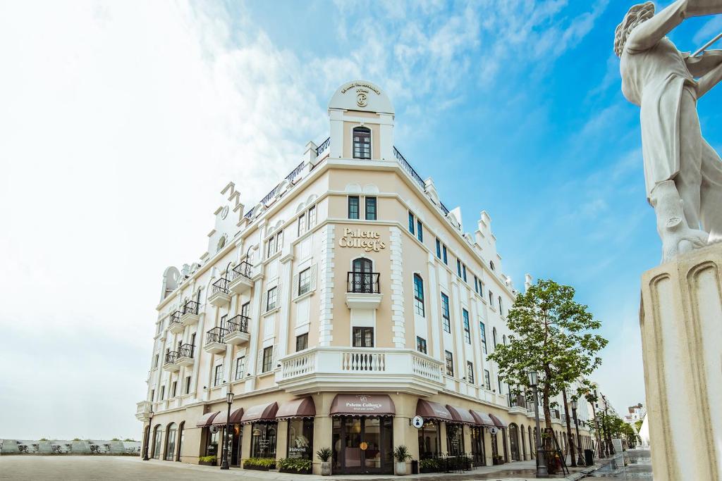 下龙湾Palette Collect's Boutique Hotel Ha Long的一座白色的大建筑,前面有雕像