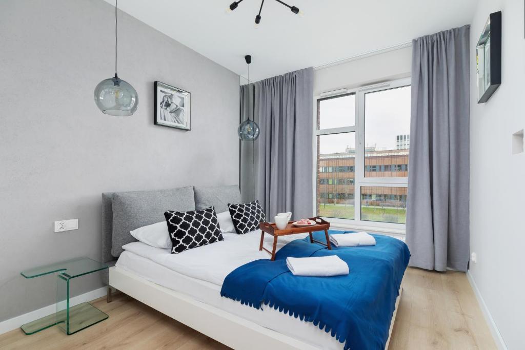 克拉科夫Lotniczówka Apartments by Renters Prestige的一间卧室配有一张带蓝色毯子的床